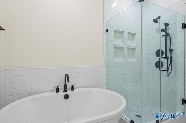 full bathroom with a soaking tub and a shower stall