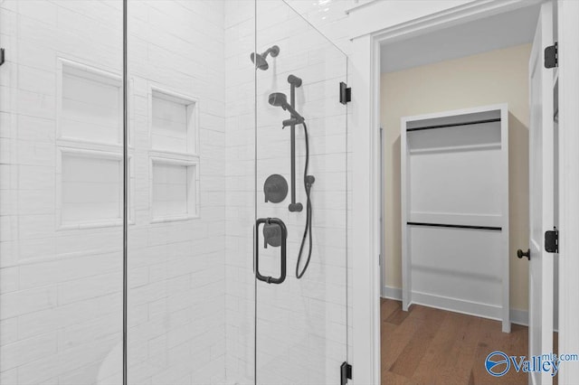 bathroom featuring wood finished floors and a shower stall