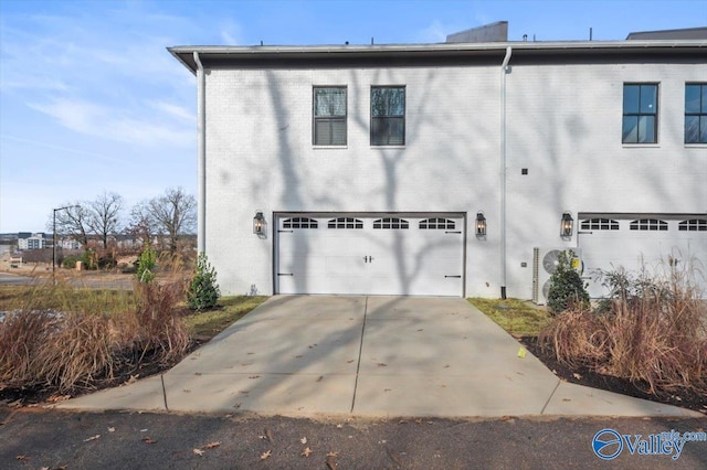 view of side of home featuring concrete driveway, brick siding, and an attached garage