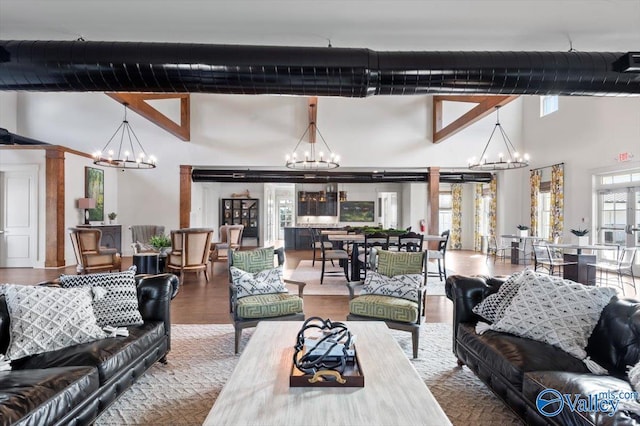 living room with wood finished floors, ornate columns, a high ceiling, and an inviting chandelier