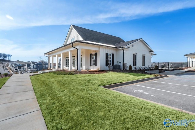 view of side of property featuring metal roof, cooling unit, a lawn, uncovered parking, and board and batten siding