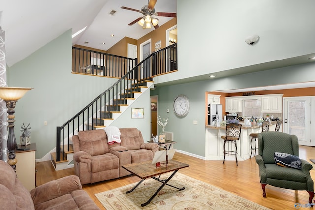 living room featuring light hardwood / wood-style flooring, ceiling fan, and a high ceiling