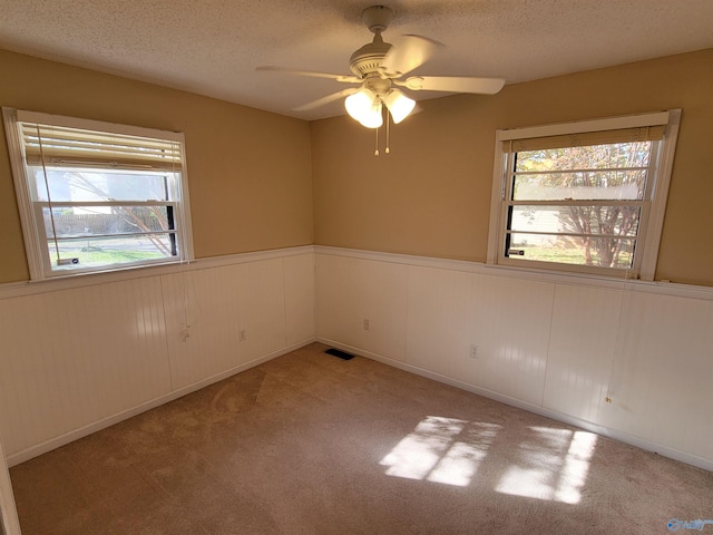 spare room with a textured ceiling, ceiling fan, and light carpet