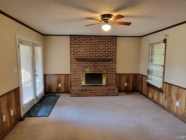 unfurnished living room with light carpet, a brick fireplace, a textured ceiling, ceiling fan, and wood walls