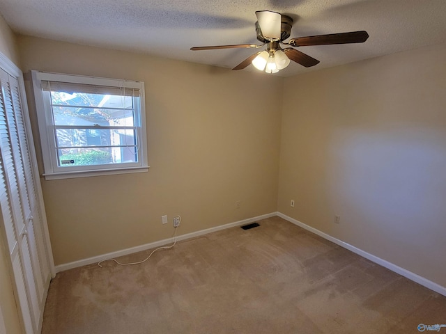 carpeted empty room featuring ceiling fan and a textured ceiling