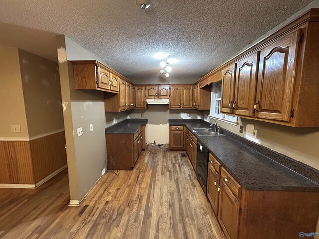 kitchen featuring wood walls, sink, a textured ceiling, black dishwasher, and dark hardwood / wood-style flooring