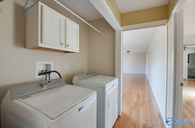 laundry area featuring independent washer and dryer, cabinets, and light hardwood / wood-style floors