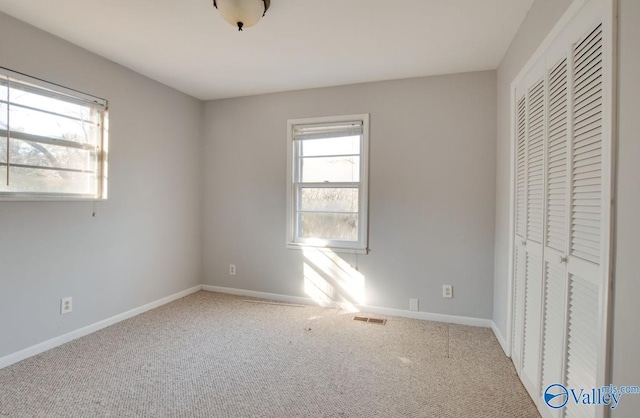 unfurnished bedroom featuring a closet and light colored carpet