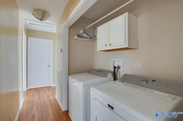 laundry room featuring independent washer and dryer, cabinets, and light hardwood / wood-style flooring