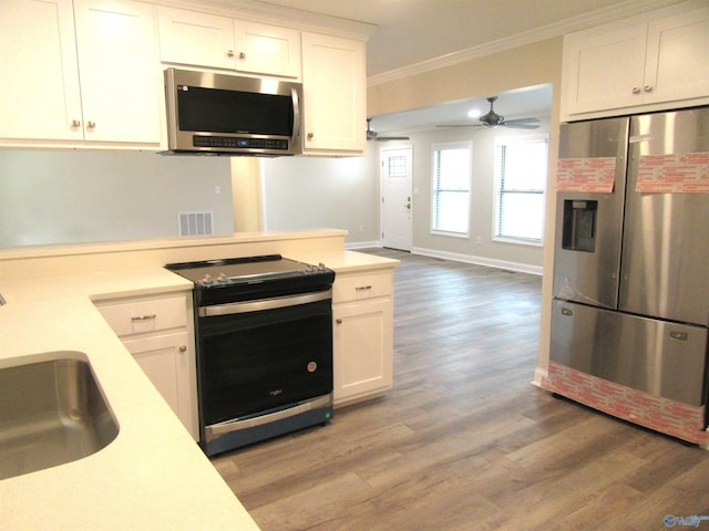 kitchen with sink, crown molding, light wood-type flooring, white cabinetry, and stainless steel appliances