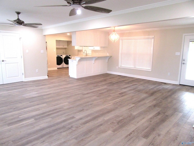 unfurnished living room with washer and dryer, crown molding, dark wood-type flooring, and sink