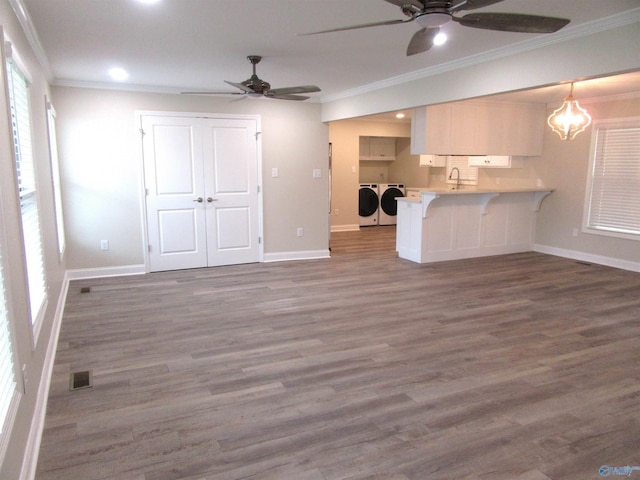 unfurnished living room with ornamental molding, washer and clothes dryer, dark wood-type flooring, and a notable chandelier