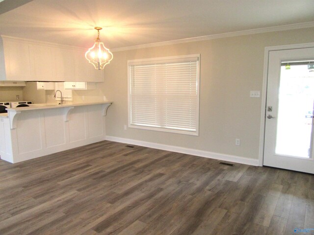 kitchen featuring crown molding, dark hardwood / wood-style flooring, white cabinets, and hanging light fixtures