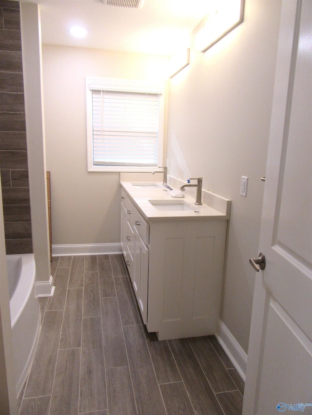 bathroom with a bath, hardwood / wood-style floors, and vanity