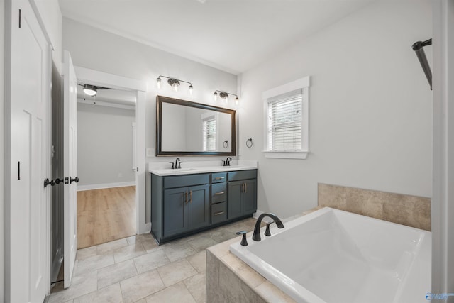 bathroom with tile patterned flooring, vanity, and tiled tub