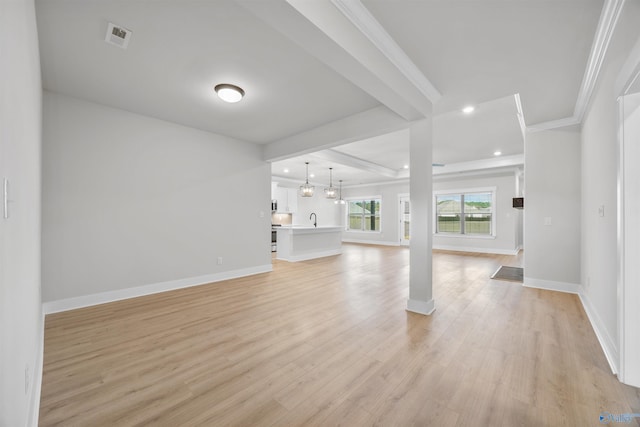 unfurnished living room with ornamental molding, light hardwood / wood-style flooring, sink, and beam ceiling