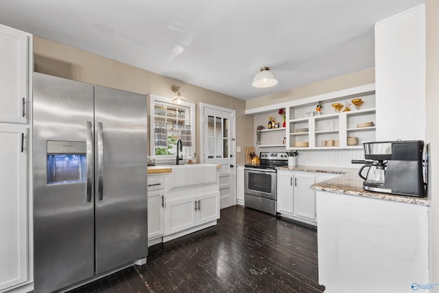 kitchen with light stone countertops, white cabinetry, sink, and appliances with stainless steel finishes