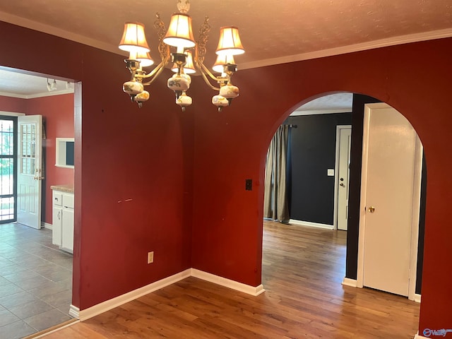 unfurnished dining area featuring crown molding, an inviting chandelier, and light hardwood / wood-style floors