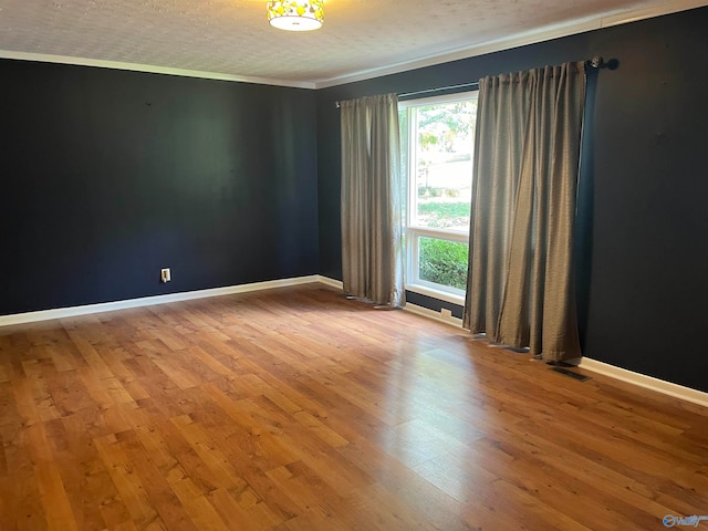 unfurnished room with hardwood / wood-style flooring, ornamental molding, and a textured ceiling