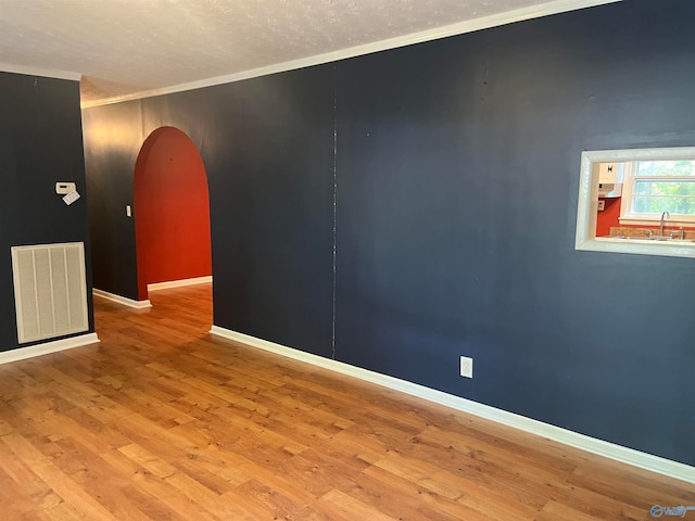 spare room with hardwood / wood-style flooring, sink, a textured ceiling, and ornamental molding