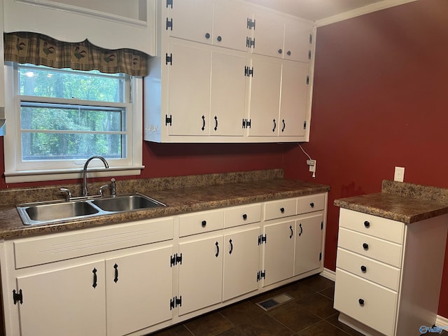 kitchen featuring white cabinetry, dark tile patterned floors, and sink