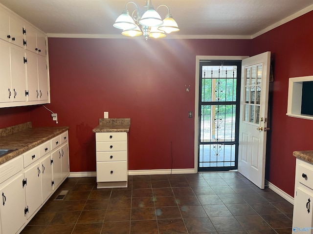 kitchen featuring decorative light fixtures, white cabinetry, and ornamental molding