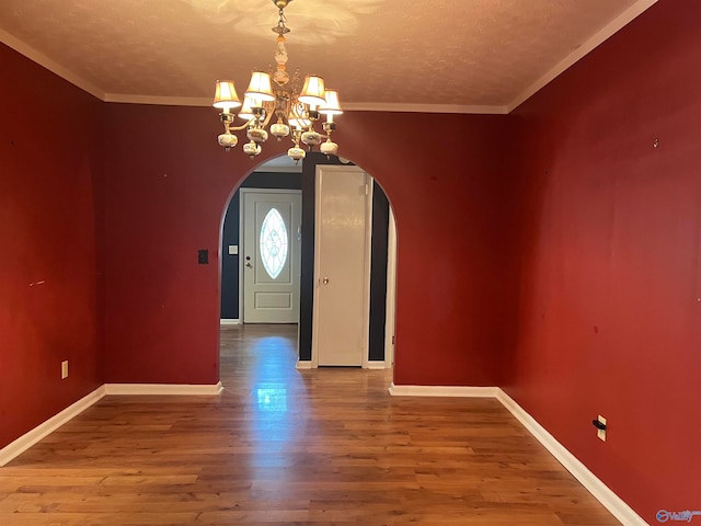 entryway featuring crown molding, a textured ceiling, wood-type flooring, and an inviting chandelier