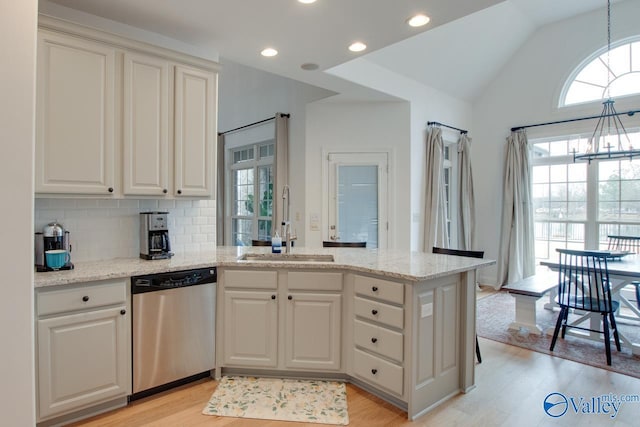 kitchen with stainless steel dishwasher, decorative light fixtures, kitchen peninsula, and sink