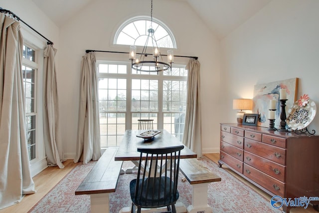 dining room with an inviting chandelier, high vaulted ceiling, and light wood-type flooring