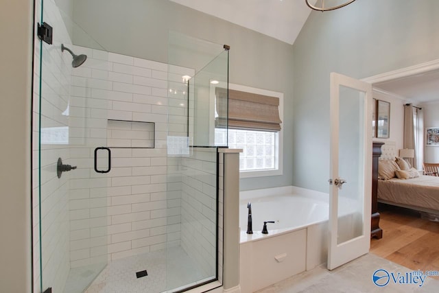 bathroom with wood-type flooring, independent shower and bath, and vaulted ceiling