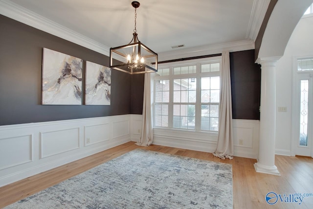 dining area featuring a notable chandelier, ornamental molding, light hardwood / wood-style flooring, and ornate columns