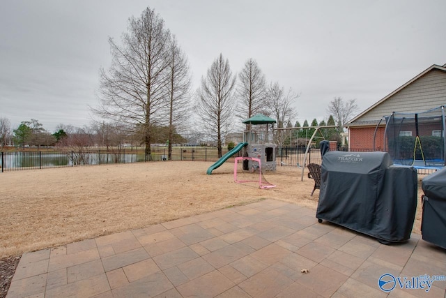 view of play area with a water view, a trampoline, and a patio area