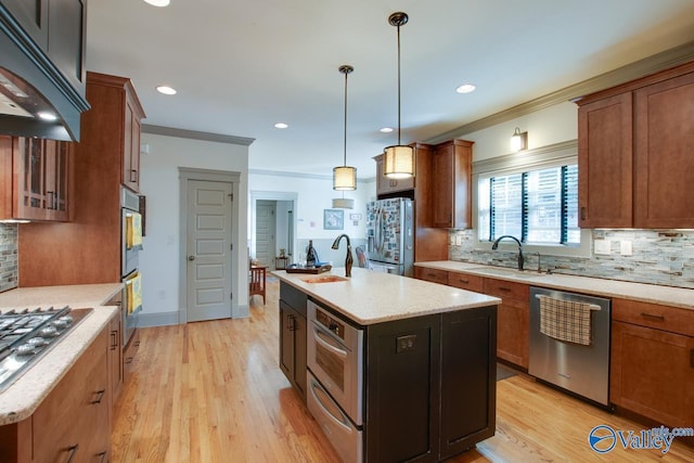 kitchen featuring sink, crown molding, hanging light fixtures, stainless steel appliances, and a kitchen island with sink