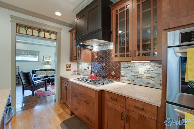 kitchen featuring backsplash, light stone countertops, light hardwood / wood-style floors, and appliances with stainless steel finishes