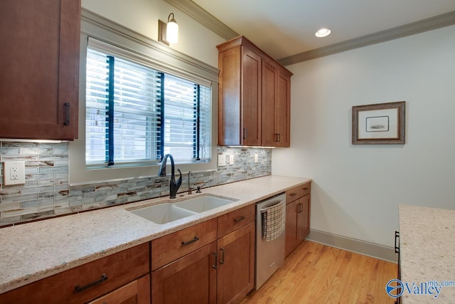 kitchen with sink, ornamental molding, stainless steel dishwasher, light stone counters, and light wood-type flooring