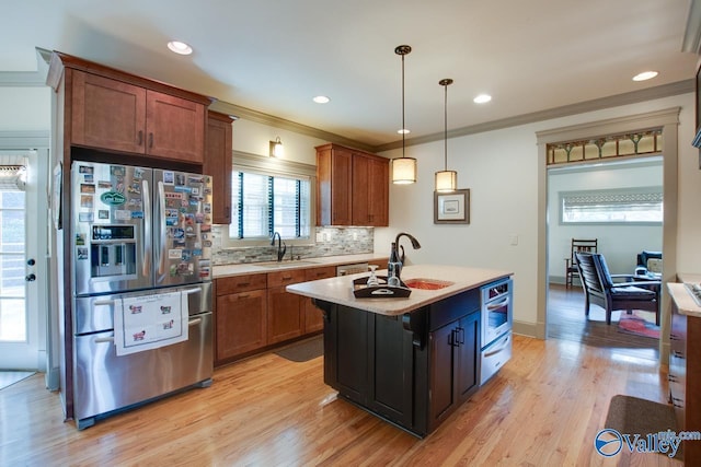 kitchen with stainless steel appliances, a kitchen island, sink, and hanging light fixtures