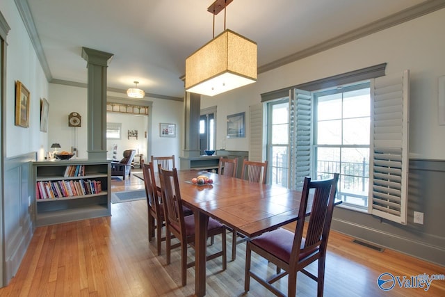 dining area with hardwood / wood-style floors, ornamental molding, and ornate columns