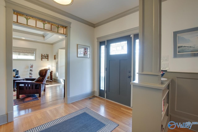 foyer featuring ornamental molding, light hardwood / wood-style floors, and a wealth of natural light