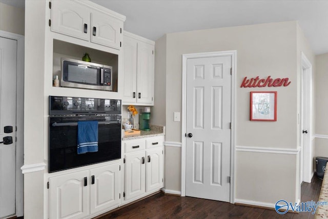 kitchen featuring white cabinets, dark wood-type flooring, and black oven