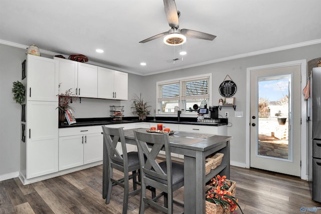 kitchen with ceiling fan, dark wood-type flooring, white cabinetry, and ornamental molding