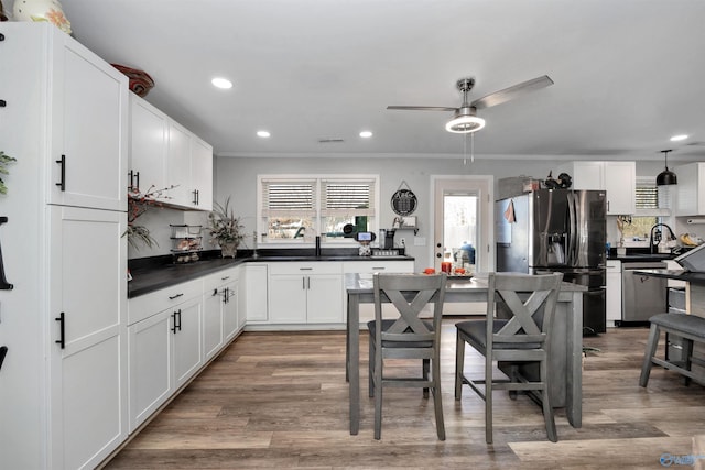 kitchen with stainless steel appliances, wood-type flooring, white cabinets, and tasteful backsplash