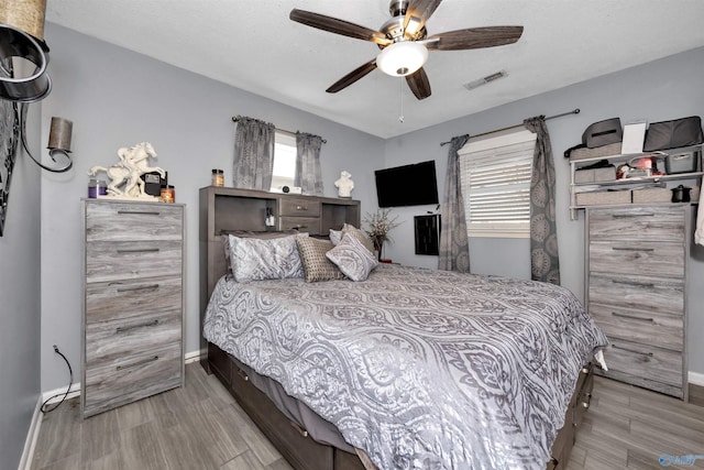 bedroom with ceiling fan, light wood-type flooring, and a textured ceiling