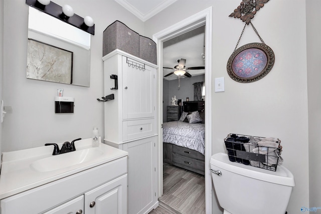 bathroom with toilet, hardwood / wood-style floors, ceiling fan, ornamental molding, and vanity