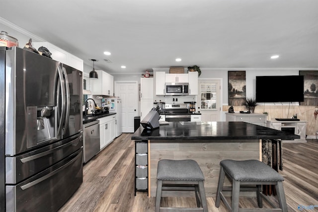 kitchen with stainless steel appliances, ornamental molding, white cabinets, and a breakfast bar