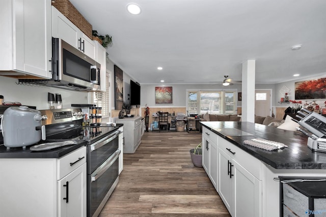 kitchen with white cabinetry, stainless steel appliances, ceiling fan, ornamental molding, and hardwood / wood-style flooring