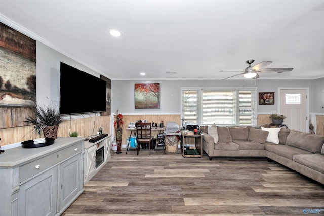 living room with ceiling fan, crown molding, light hardwood / wood-style flooring, and wood walls