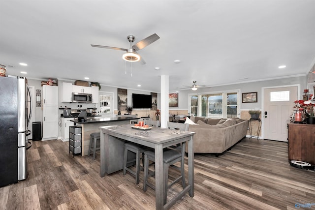 kitchen with white cabinets, crown molding, a breakfast bar area, and appliances with stainless steel finishes