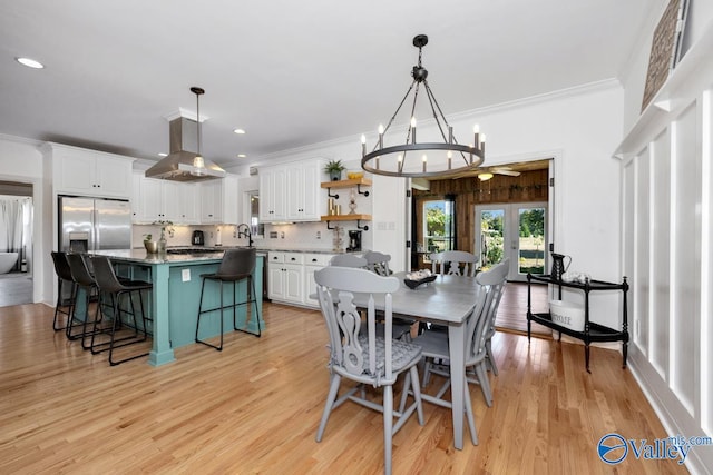 dining area with crown molding, sink, a notable chandelier, and light wood-type flooring