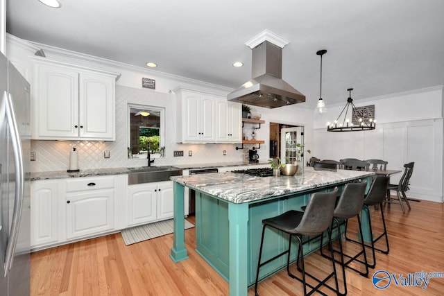 kitchen featuring island range hood, sink, a center island, a breakfast bar, and white cabinets