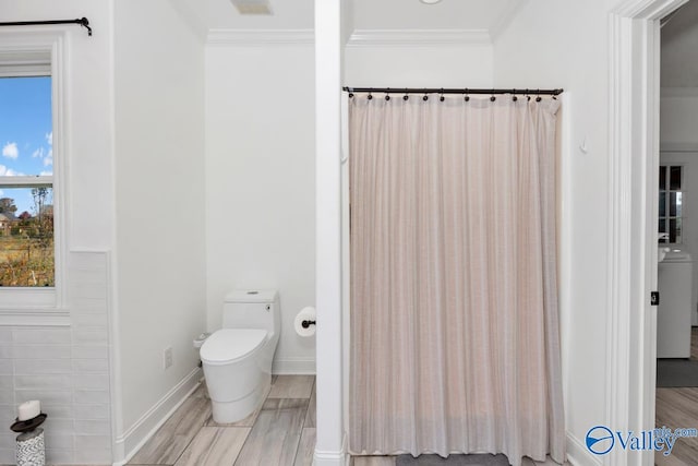 bathroom featuring toilet, crown molding, hardwood / wood-style flooring, and washer / dryer